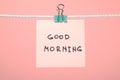 Pink paper note on clothesline with text Ã¢â¬ÅGood MorningÃ¢â¬Â Royalty Free Stock Photo